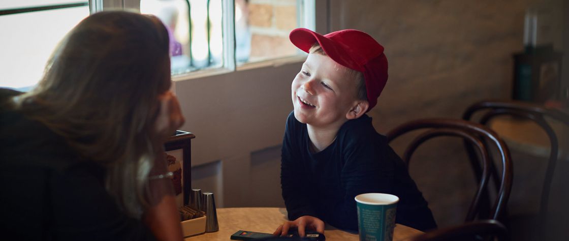 A child in a red cap enjoys a beverage with his mother at a table in the Dome Cafe in the Premier Mill Hotel