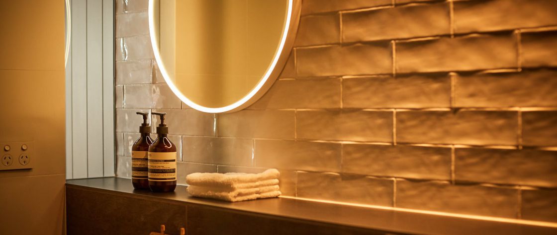 Close up of the hotel bathroom with led lit circle mirror, brass taps and luxury toiletries